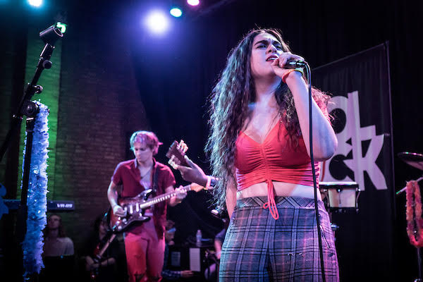 Haley Solomito, alongside fellow members of the School of Rock program, performing lead vocals in front of a live crowd