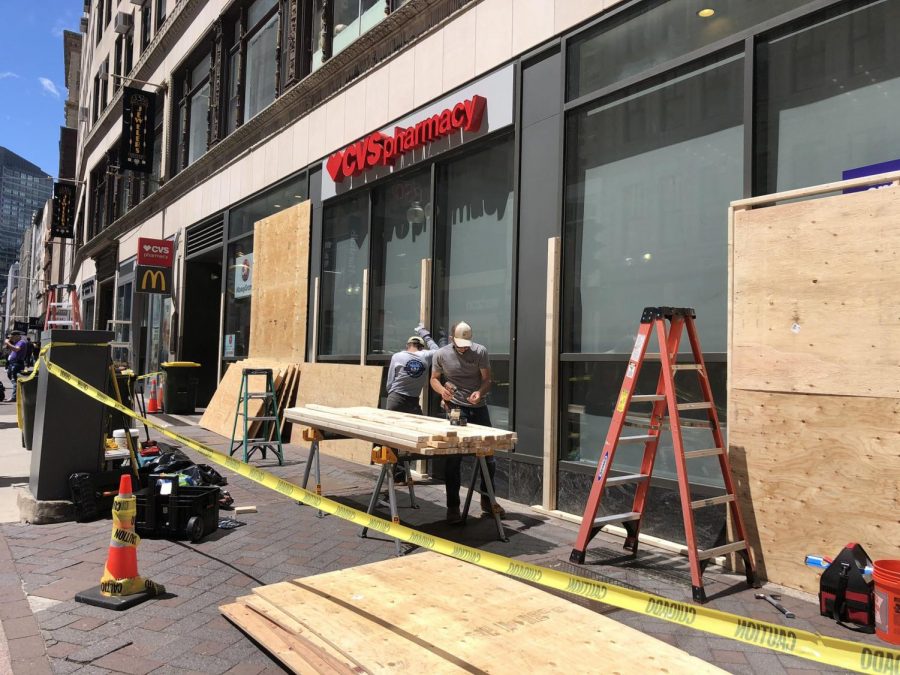 Workers put wooden boards over the windows of a CVS in Dowtown Crossing Monday morning. 