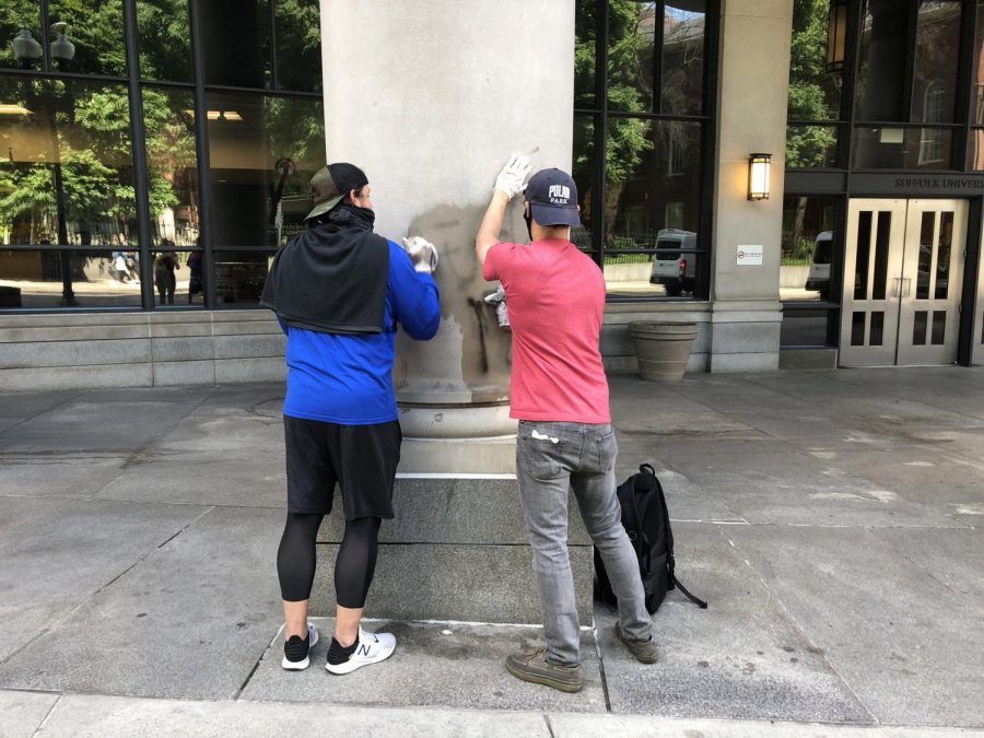 Good Samaritans clean off graffiti from the outside of Sargent Hall Monday morning, after protests broke in Boston Sunday night.  