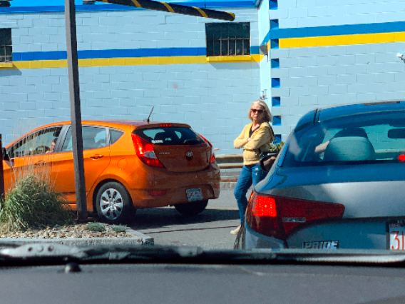 A woman standing in a drive-thru lane waiting to order. 