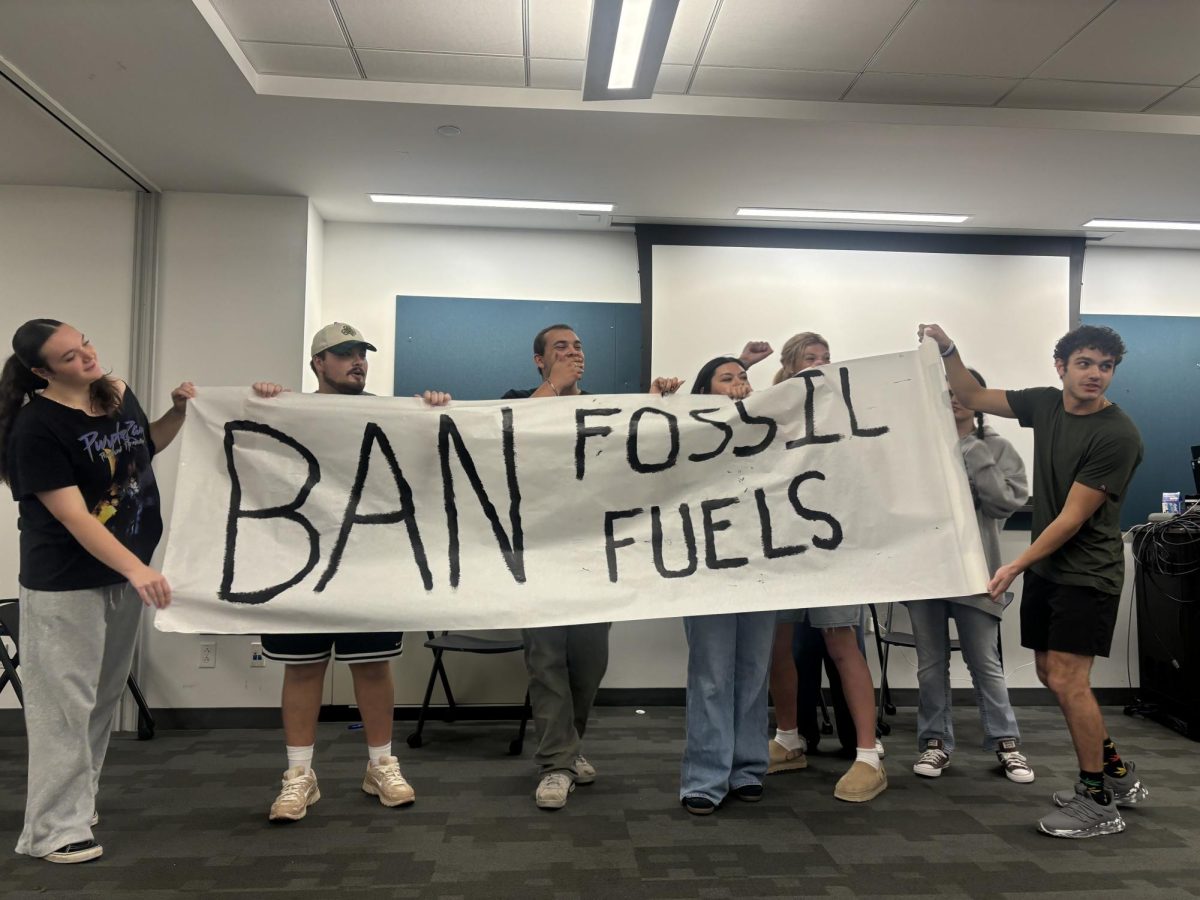 Part of the 'Who's Askin' sketch comedy club holding up a sign during their first show of the semester.