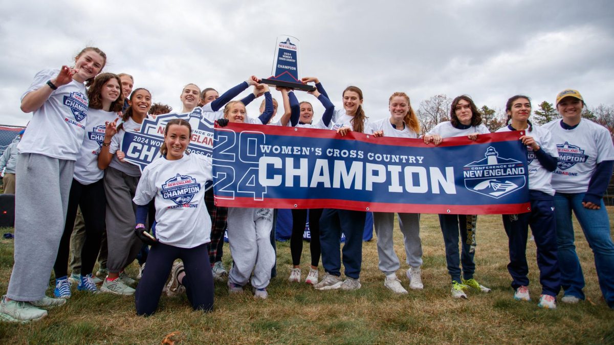 The women's cross country team holding up a CNE championship banner after their win (courtesy Cole Bolduc)