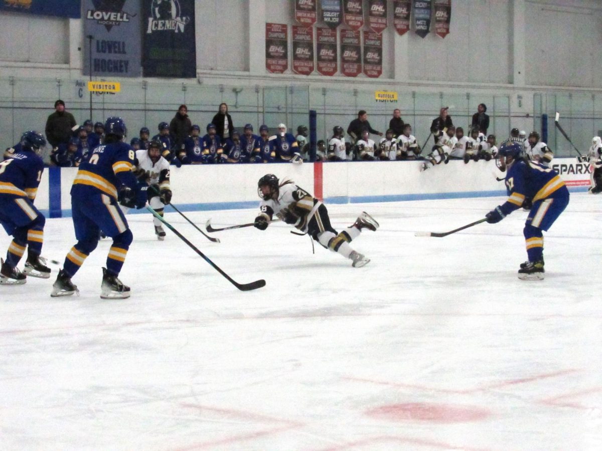 Sophomore forward Aiden Levee-Oshiro shoots the puck while falling to the ice.