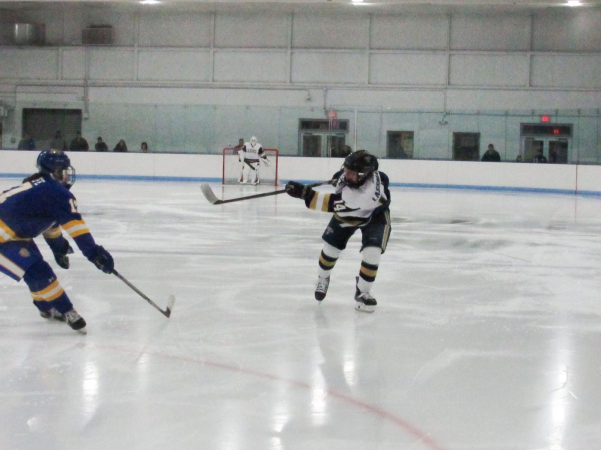 Senior and captain Sammy Lassman shooting the puck in traffic during a home game against Johnson & Wales University.