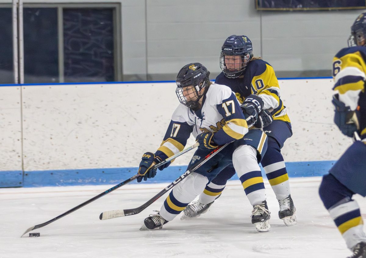 Junior forward Bella Schmidt handling the puck while fending off a defender.