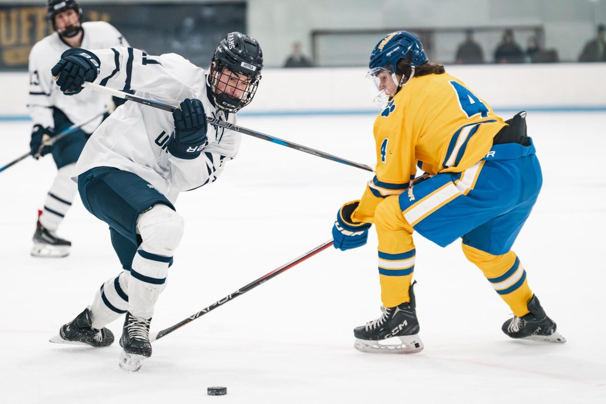 Daniel McKiernan chasing the puck while battling Johnson & Wales forward Brad Crook.