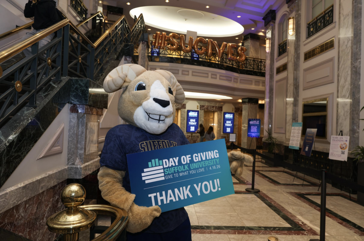 Rammy posing with "Day of Giving" sign in the 73 Tremont lobby.